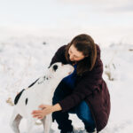Photo of Sarah Wilson, DVM, snuggling with her dog in the snow for decorative purposes as the featured image.