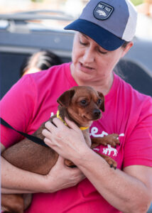 Sarah Wilson, DVM working at a community vaccine clinic holding a small dog for decorative purposes.