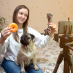 Female pet blogger. Woman recording video review of pet toys product with pug on her smartphone